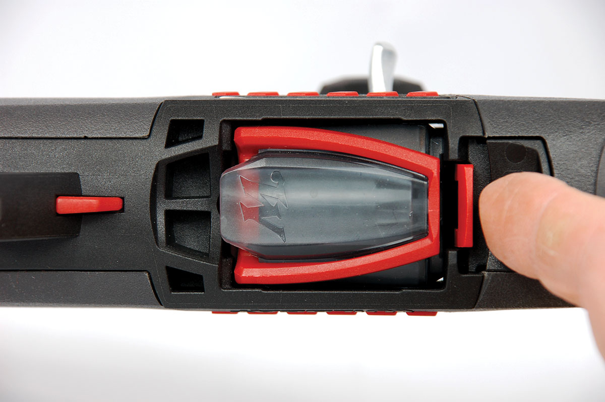 The forward magazine latch is the second option to release the magazine. The red blade-type button on the far left-hand side of the photo is the manual bolt hold-open latch.